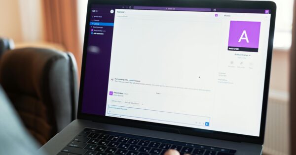 Person using a laptop with an online communication platform, showcasing modern work tech.